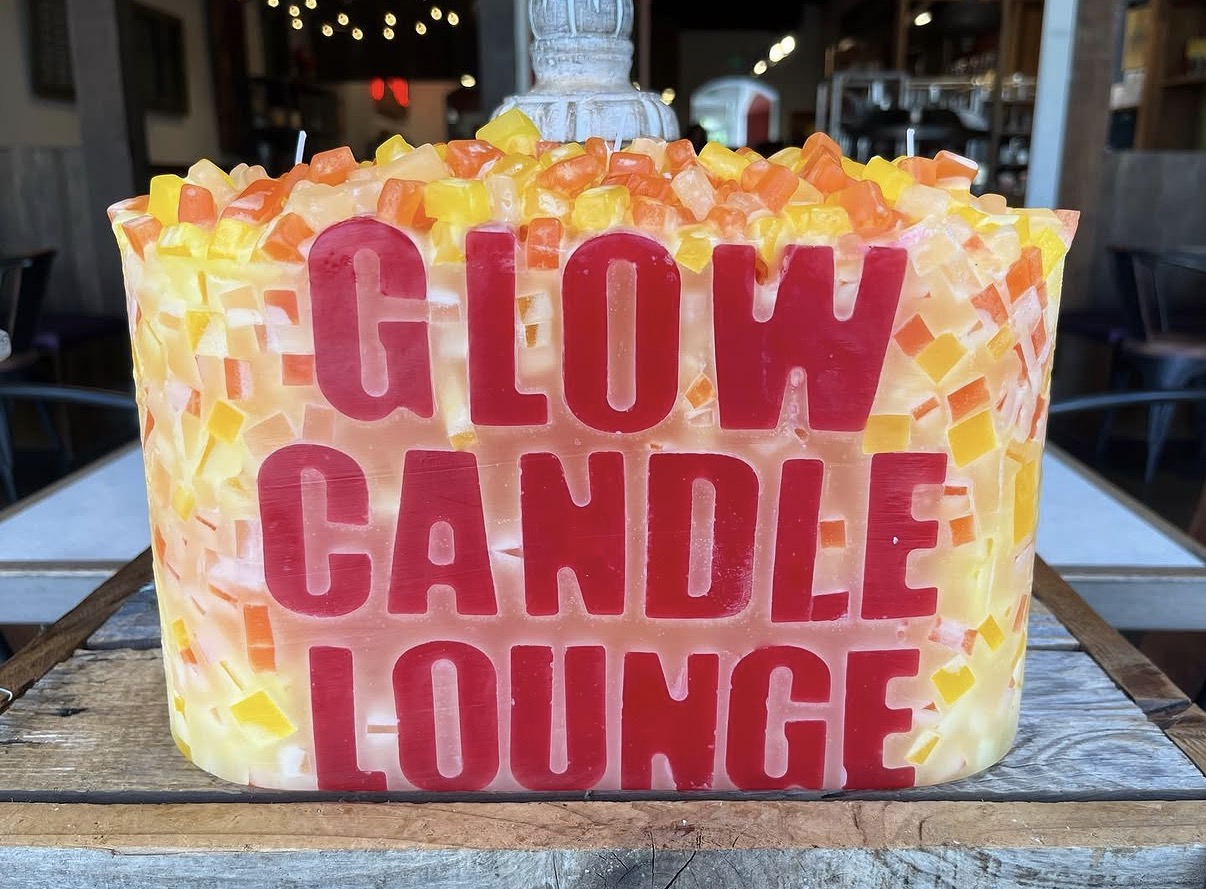 Large Glow Candle Lounge branded candle with orange and yellow wax pieces